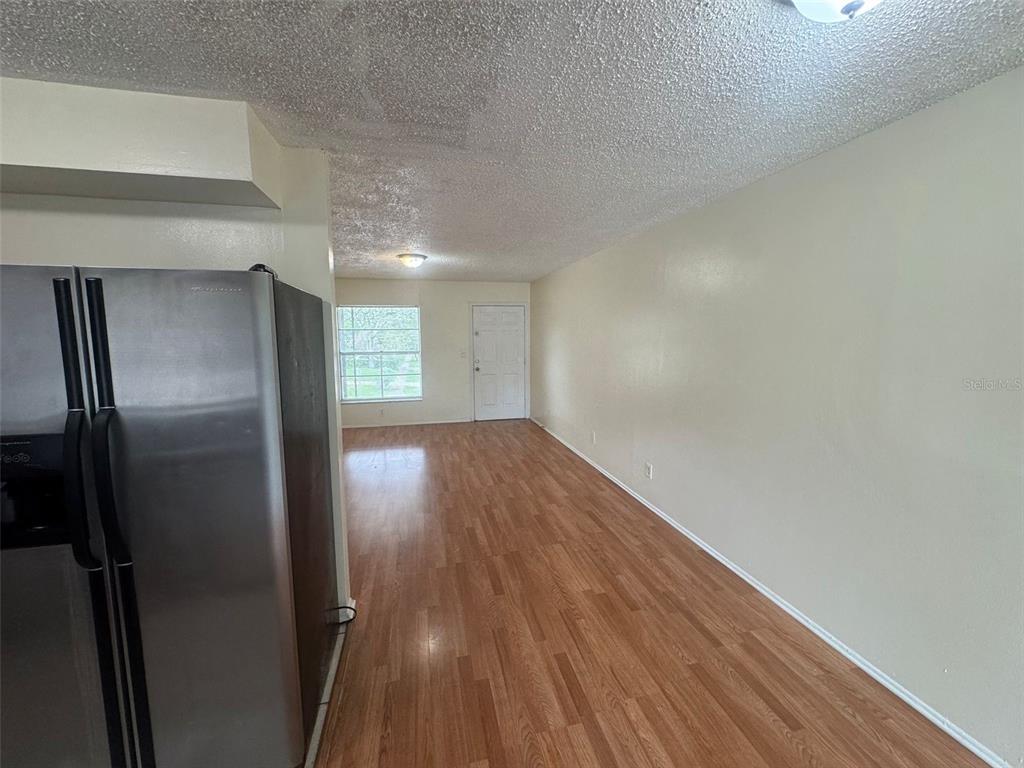 A view of a room with wood-look flooring, a stainless steel refrigerator, and a door — 2800 E 113TH AVENUE UNIT B1204, TAMPA, FL