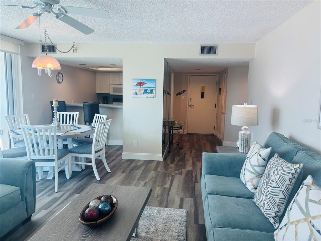 A living and dining area features wood-look flooring, a blue sofa, and a round table — 6518 MIDNIGHT PASS ROAD UNIT 209, SARASOTA, FL