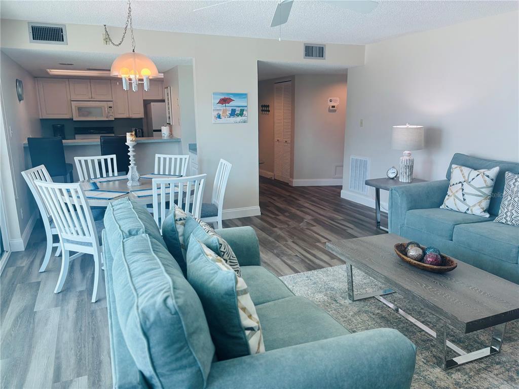 A living room and dining area feature light wood-look flooring, blue sofas, and white furniture — 6518 MIDNIGHT PASS ROAD UNIT 209, SARASOTA, FL