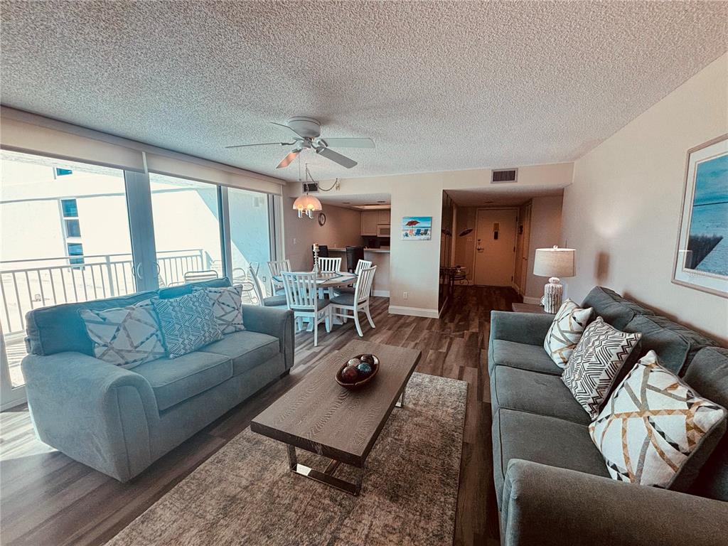 A living room with two grey sofas, a coffee table, and a dining area — 6518 MIDNIGHT PASS ROAD UNIT 209, SARASOTA, FL