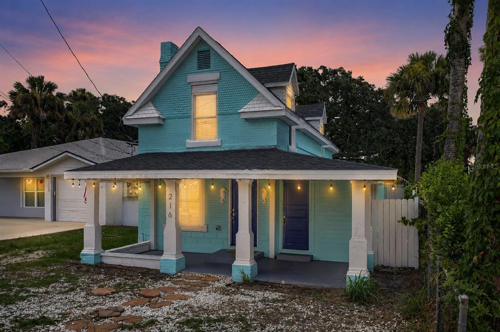 A two-story turquoise house with a covered front porch and white columns at dusk — 216 N HALIFAX AVENUE, DAYTONA BEACH, FL