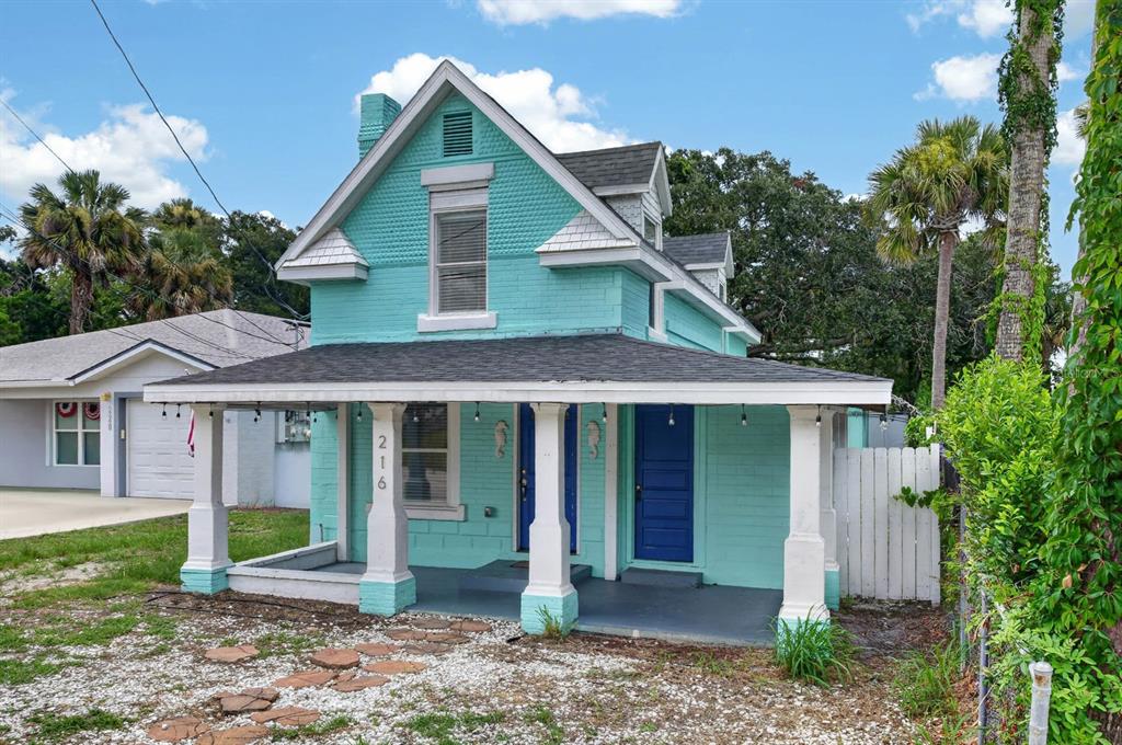A two-story turquoise house with a front porch, white columns, and a dark blue door — 216 N HALIFAX AVENUE, DAYTONA BEACH, FL