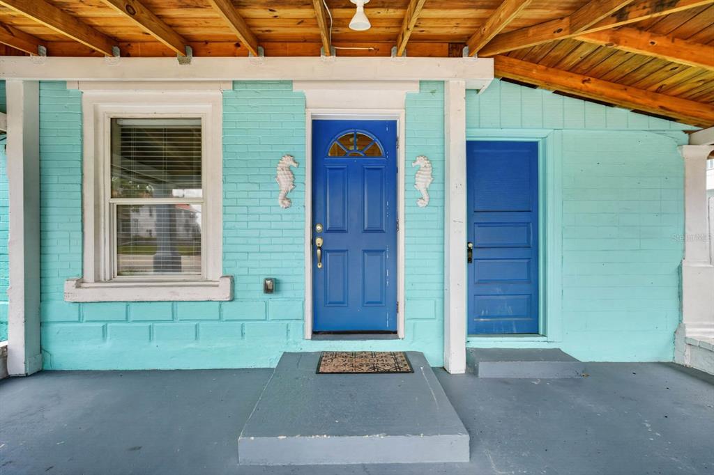 A turquoise brick porch features a blue front door, a secondary blue door, and wood-plank ceilings — 216 N HALIFAX AVENUE, DAYTONA BEACH, FL