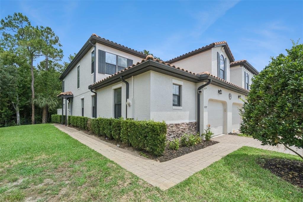 A two-story townhouse with a stucco exterior, stone accents, and a paved walkway — 8137 ROSEVILLE ROAD, DAVENPORT, FL
