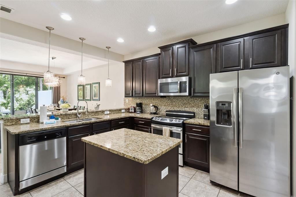 A kitchen features dark wood cabinets, granite countertops, stainless steel appliances, and a center island — 8137 ROSEVILLE ROAD, DAVENPORT, FL