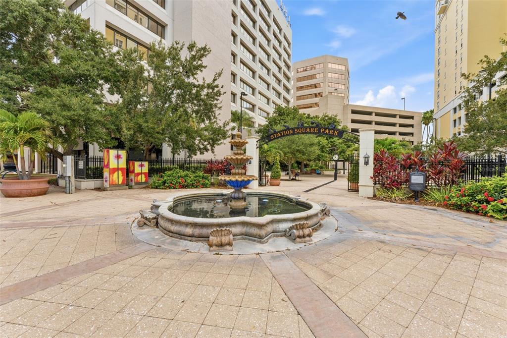A stone fountain sits in a paved plaza in front of a park entrance archway — 628 CLEVELAND STREET UNIT 1211, CLEARWATER, FL