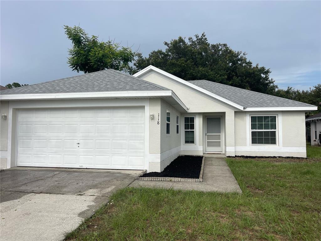A single-story house with a white stucco exterior, a gray shingled roof, and a garage — 118 SPRINGFIELD PASS, DAVENPORT, FL
