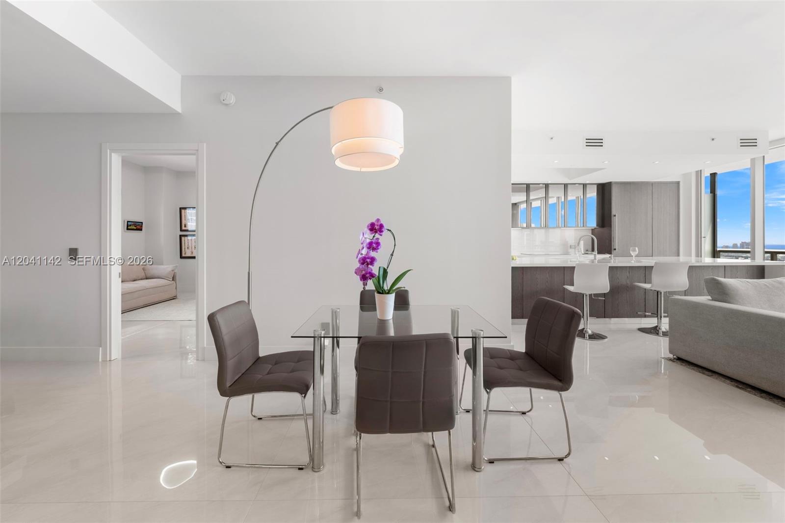 A dining area with a glass table and four chairs sits in an open-concept apartment — 888 Biscayne Blvd # 5404, Miami FL 33132, MIAMI, FL