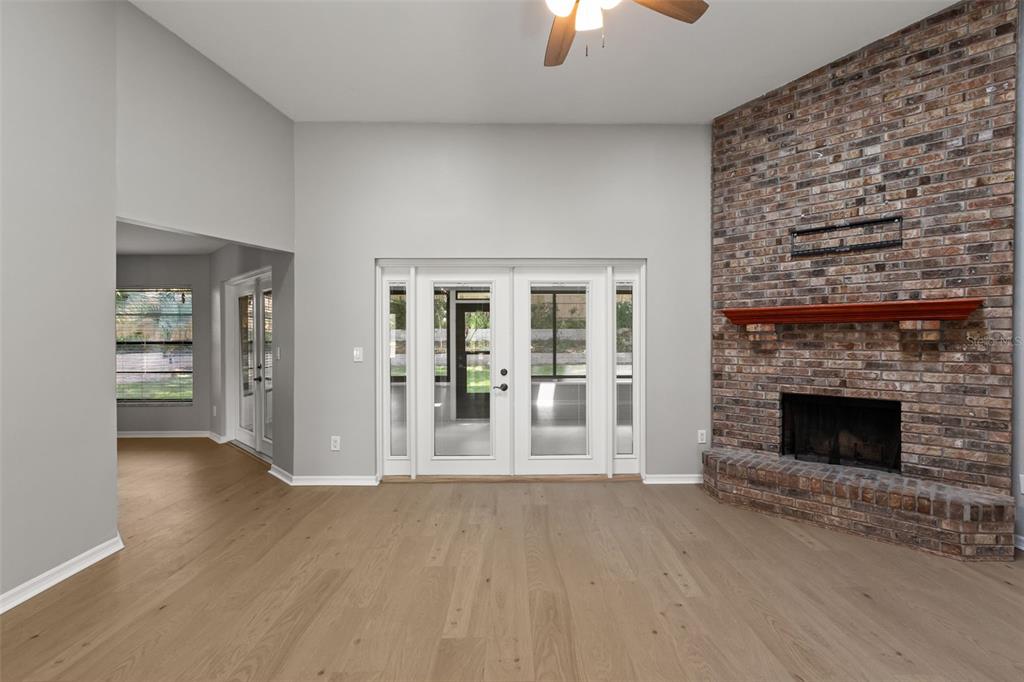 A living room features light wood flooring, a brick fireplace, and glass double doors — 925 RED DANDY DRIVE, ORLANDO, FL