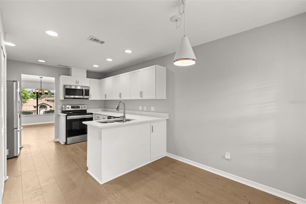 A kitchen with white cabinets, stainless steel appliances, and light wood flooring — 925 RED DANDY DRIVE, ORLANDO, FL