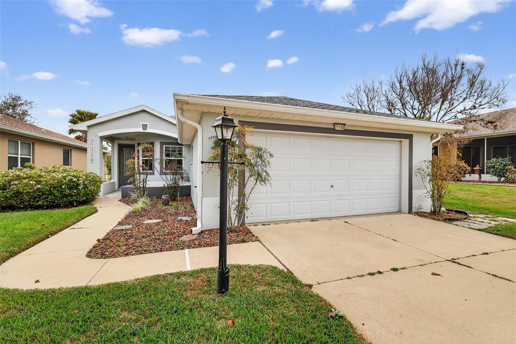 A single-story house with a white garage, a front walkway, and a lamp post — 27106 GREENFLY ORCHID LANE, LEESBURG, FL