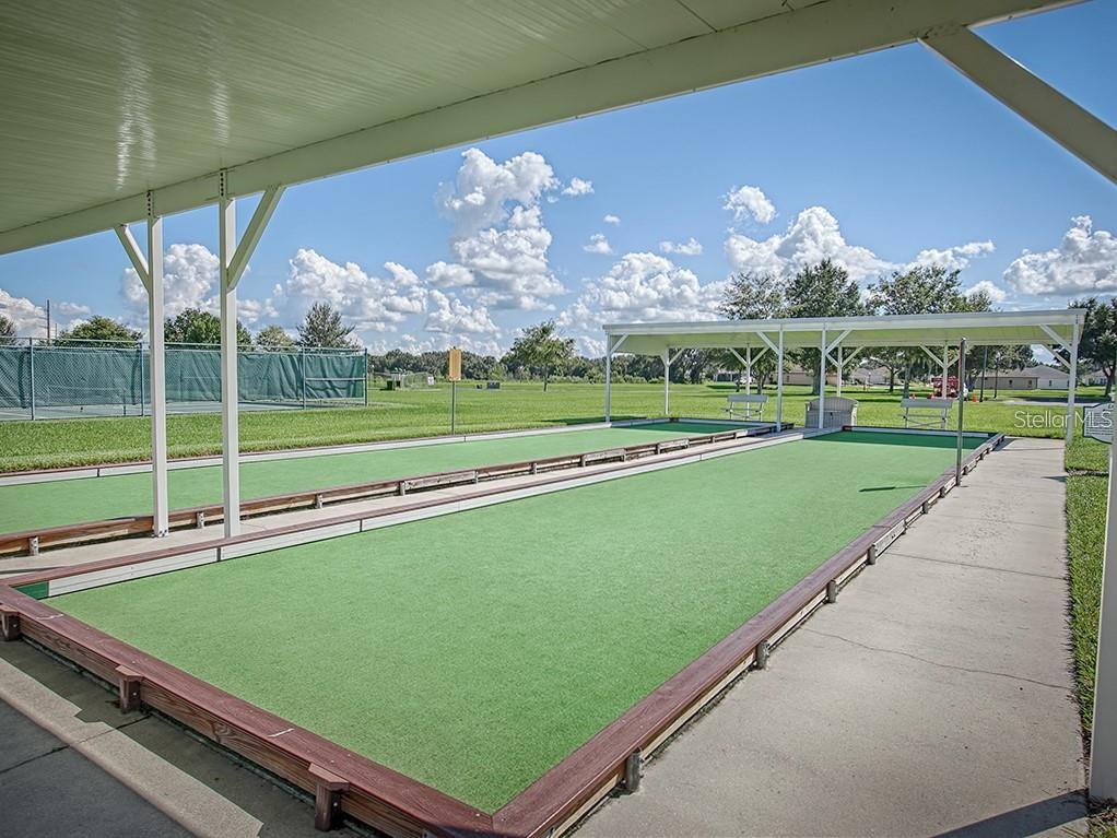 An outdoor bocce ball court with a covered seating area under a blue sky — 27106 GREENFLY ORCHID LANE, LEESBURG, FL