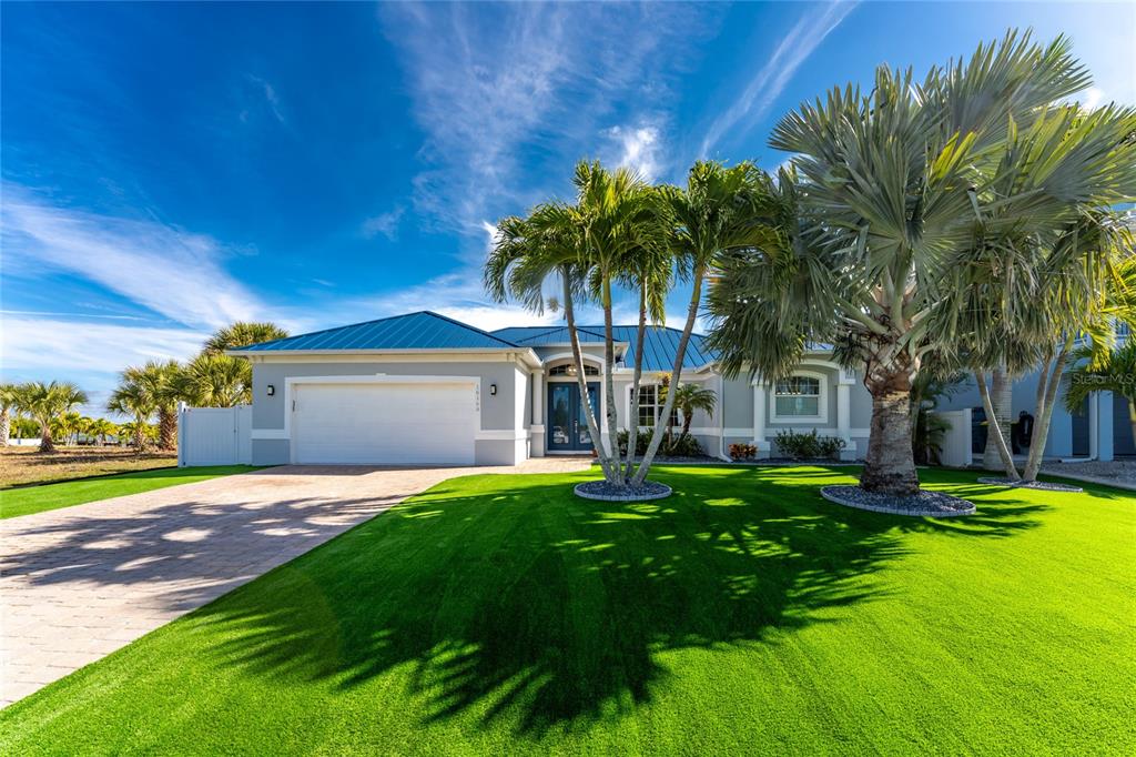 A single-story house with a blue metal roof, white garage, and palm trees on grass — 16168 LA BARGE CIRCLE, PORT CHARLOTTE, FL