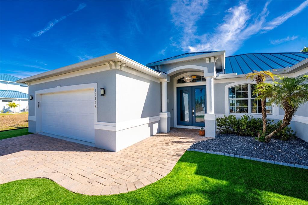 A single-story house exterior with a paved driveway, a two-car garage, and a blue door — 16168 LA BARGE CIRCLE, PORT CHARLOTTE, FL