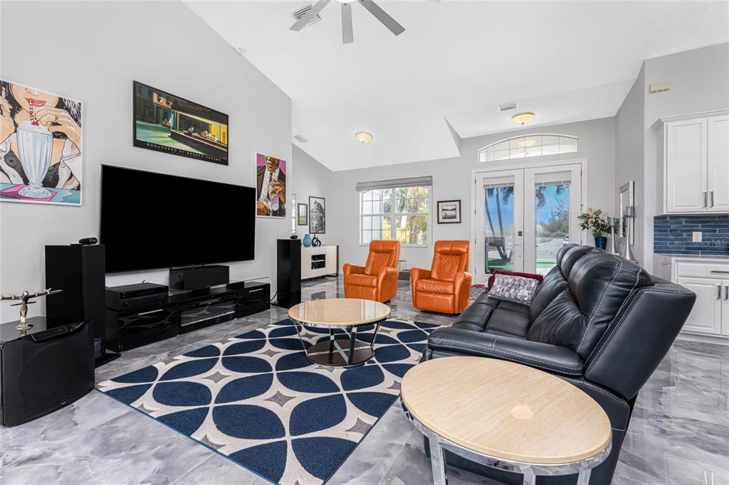 A living room with a large television, orange recliners, a black sofa, and patterned rug — 16168 LA BARGE CIRCLE, PORT CHARLOTTE, FL