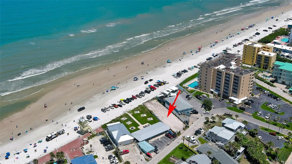 An aerial view shows a beachside property with a parking lot and nearby hotel buildings — 0 BUENOS AIRES AVENUE, NEW SMYRNA BEACH, FL