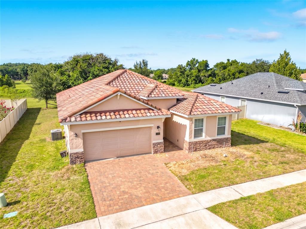 An aerial view of a single-story house with a tiled roof and a paved driveway — 480 BELLISSIMO PLACE, HOWEY IN THE HILLS, FL