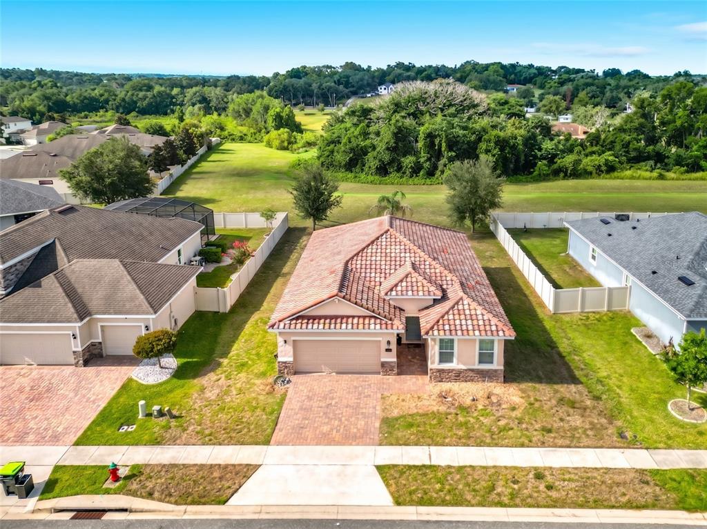 An aerial view of a single-story house with a tiled roof and a paved driveway — 480 BELLISSIMO PLACE, HOWEY IN THE HILLS, FL