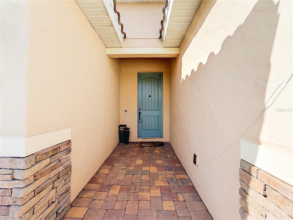 A covered entryway features a blue door, stone accents, and a paved walkway — 480 BELLISSIMO PLACE, HOWEY IN THE HILLS, FL