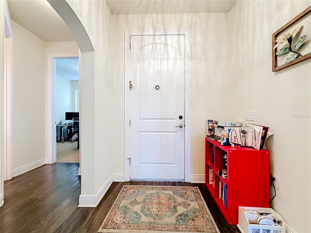 An entryway features a white front door, a red storage shelf, and a patterned area rug — 480 BELLISSIMO PLACE, HOWEY IN THE HILLS, FL