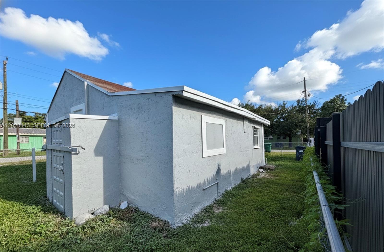 The exterior of a gray stucco building features a small door and two windows — 2103 NW 57th St, Miami FL 33142, MIAMI, FL