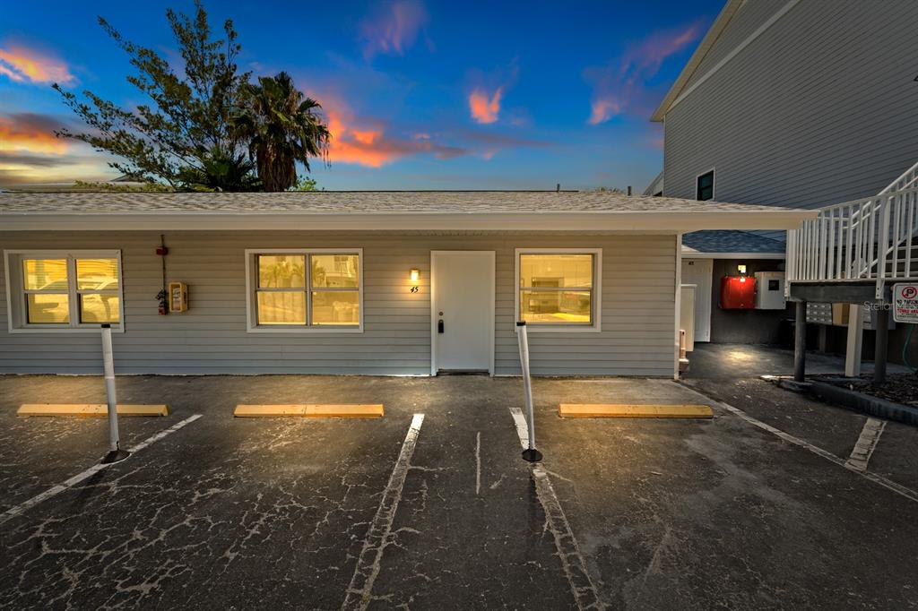 The exterior of a single-story gray building with a parking lot in the foreground — 19823 GULF BOULEVARD UNIT 45, INDIAN SHORES, FL