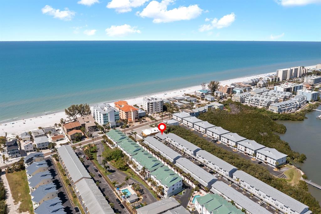 An aerial view shows a coastal residential complex with multiple buildings near a sandy beach — 19823 GULF BOULEVARD UNIT 45, INDIAN SHORES, FL
