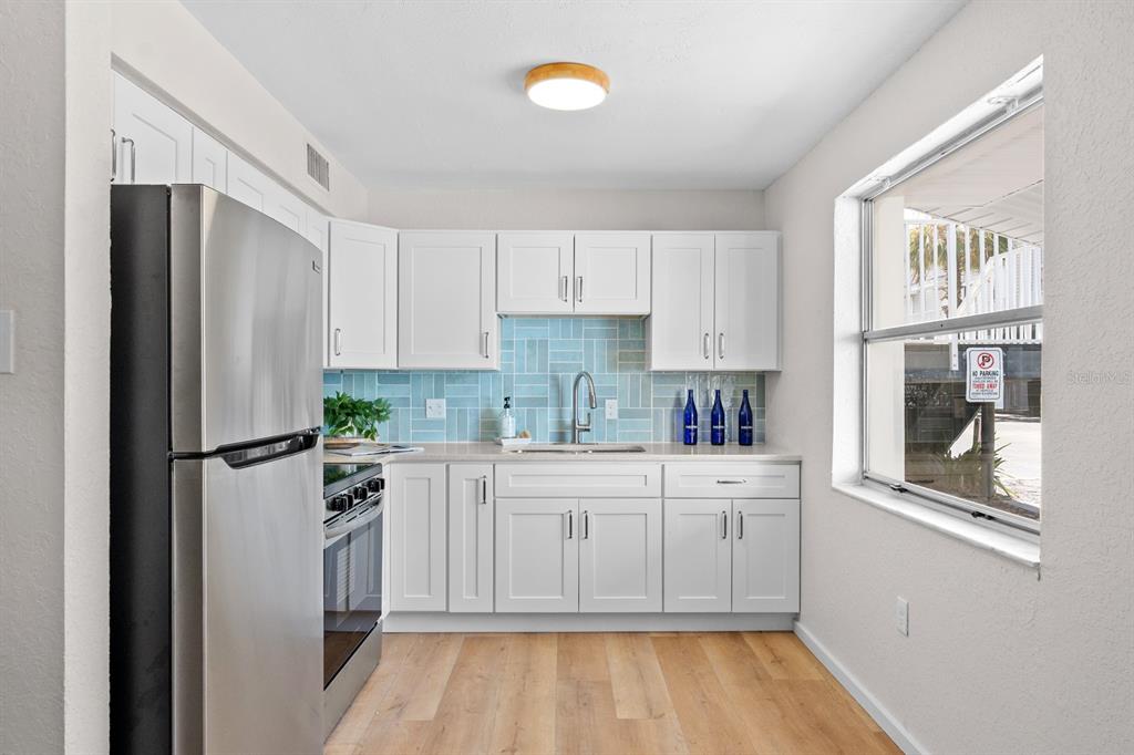 A kitchen features white cabinets, a light blue herringbone backsplash, and stainless steel appliances — 19823 GULF BOULEVARD UNIT 45, INDIAN SHORES, FL