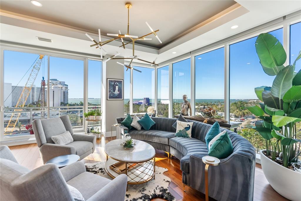 A spacious open-concept living and dining area features floor-to-ceiling windows with expansive water views — 540 N TAMIAMI TRAIL UNIT 702, SARASOTA, FL