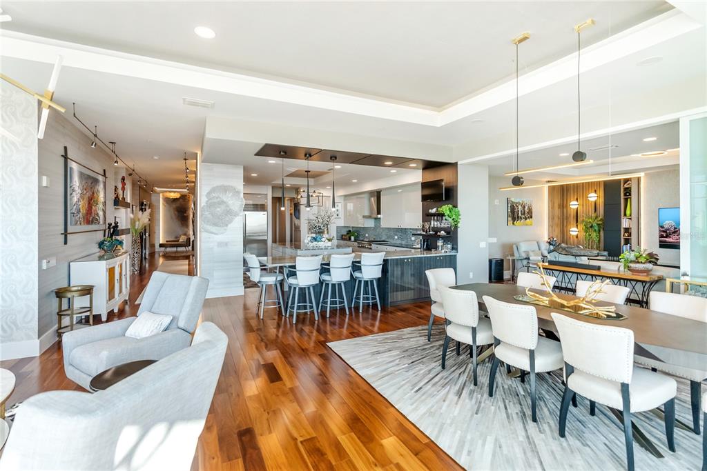 An open-concept living and dining area features hardwood floors, modern lighting, and a large kitchen — 540 N TAMIAMI TRAIL UNIT 702, SARASOTA, FL