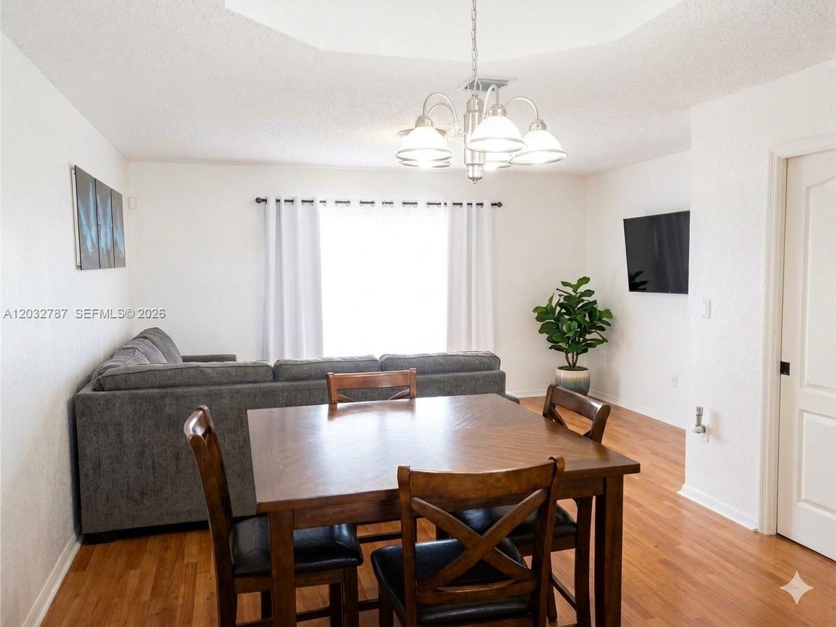 A dining area with a wooden table and chairs sits in front of a living room — 12116 SW 143rd Ln # 5, Miami FL 33186, MIAMI, FL