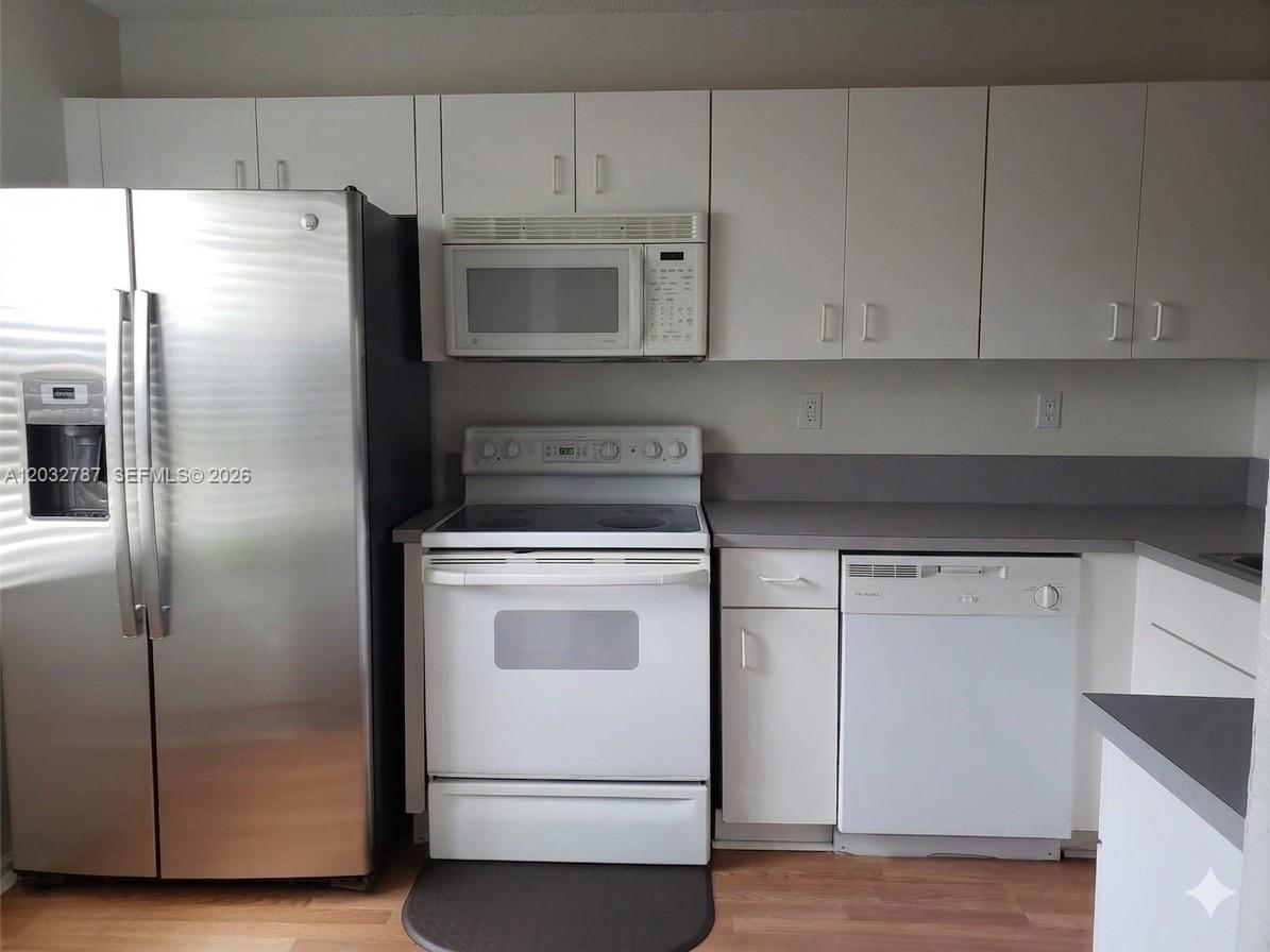 A kitchen features white cabinets, a stainless steel refrigerator, and white appliances — 12116 SW 143rd Ln # 5, Miami FL 33186, MIAMI, FL