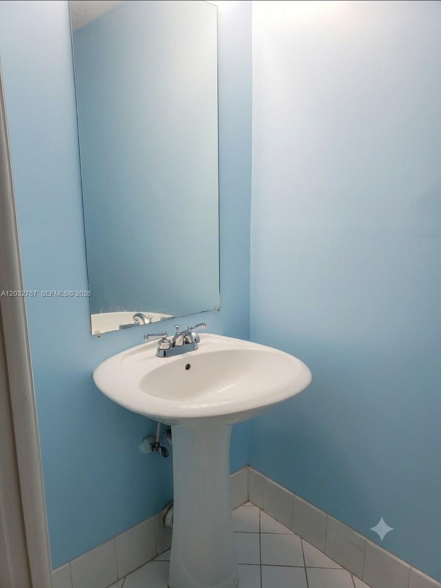 A pedestal sink with a chrome faucet sits below a wall-mounted mirror in a bathroom — 12116 SW 143rd Ln # 5, Miami FL 33186, MIAMI, FL