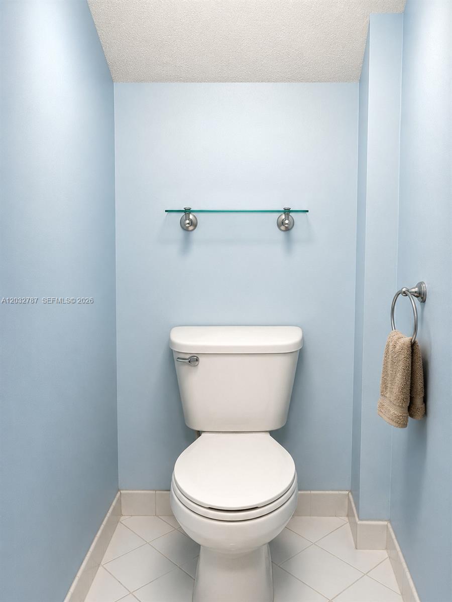 A small bathroom features light blue walls, a white toilet, and a glass wall shelf — 12116 SW 143rd Ln # 5, Miami FL 33186, MIAMI, FL
