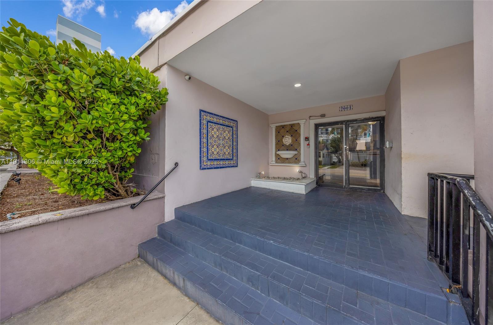 An exterior entrance features blue tiled steps leading to a glass door and decorative wall tiles — 2001 Polk St, Hollywood FL 33020, HOLLYWOOD, FL