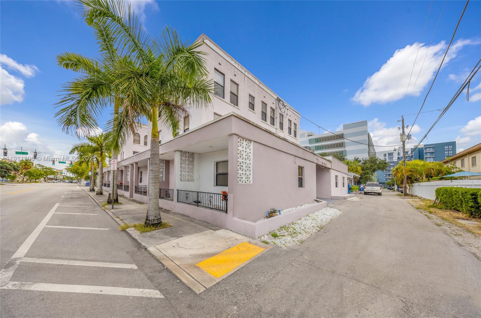 A multi-story, light-colored building with palm trees stands at a street corner — 2001 Polk St, Hollywood FL 33020, HOLLYWOOD, FL