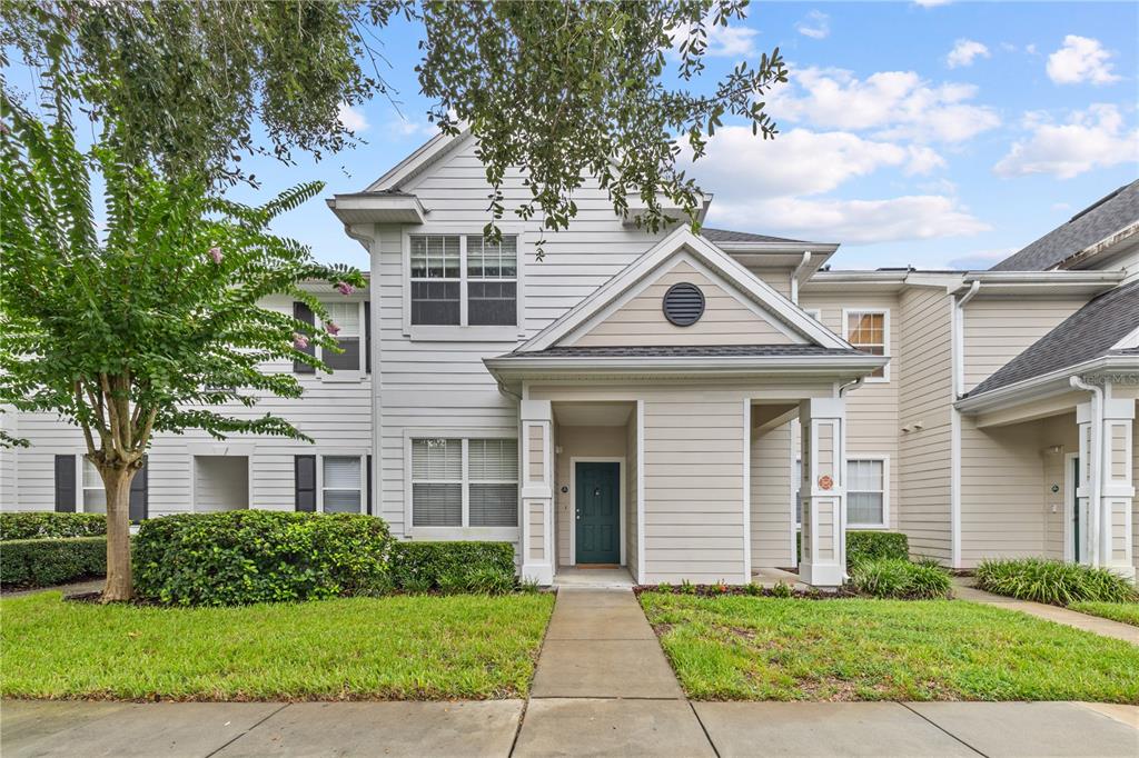 A two-story townhouse with light siding, a covered entryway, and a small front lawn — 130 SOUTHERN PECAN CIRCLE UNIT 103, WINTER GARDEN, FL