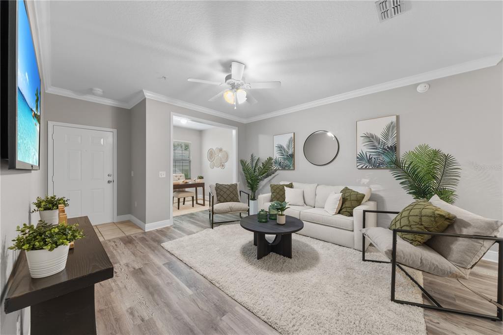 A living room features light gray walls, wood-look flooring, a white sofa, and a ceiling fan — 130 SOUTHERN PECAN CIRCLE UNIT 103, WINTER GARDEN, FL