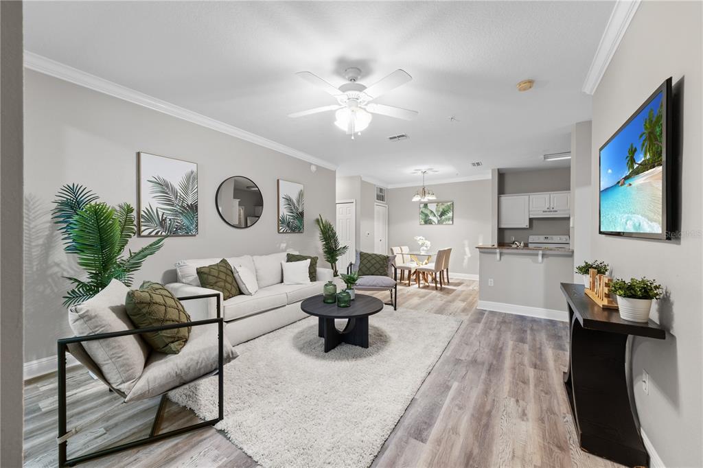 A living room with a white sofa, a round coffee table, and a wall-mounted television — 130 SOUTHERN PECAN CIRCLE UNIT 103, WINTER GARDEN, FL