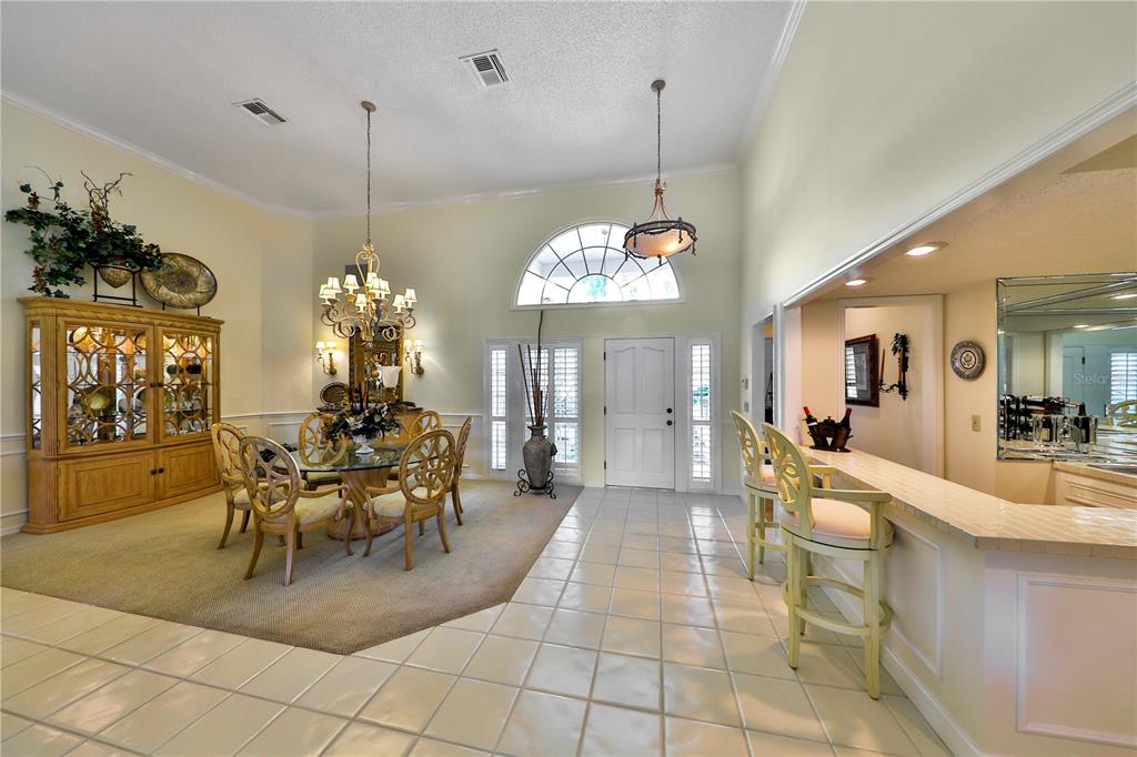 A dining room with a glass table and hutch sits beside a tiled bar area — 2446 SWEETWATER COUNTRY CLUB DRIVE, APOPKA, FL