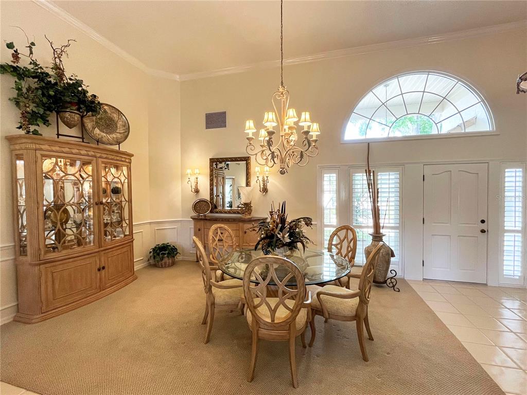 A dining room features a glass-topped table, a wooden china cabinet, and a chandelier — 2446 SWEETWATER COUNTRY CLUB DRIVE, APOPKA, FL