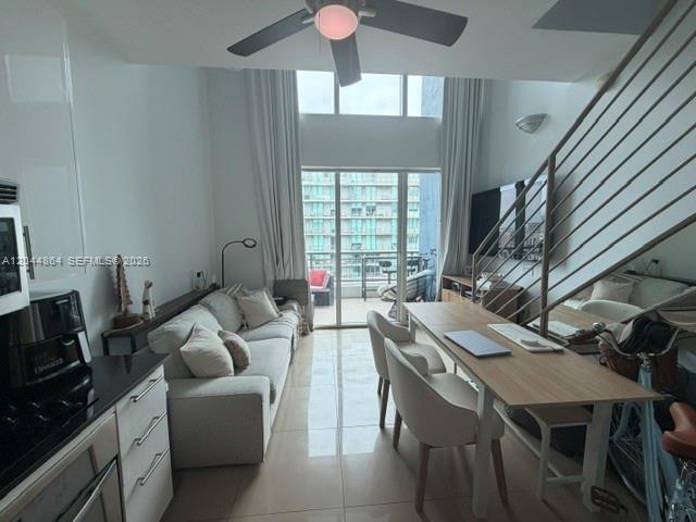 A modern living room features a sofa, dining table, staircase, and floor-to-ceiling windows — 60 SW 13th St # 4810, Miami FL 33130, MIAMI, FL