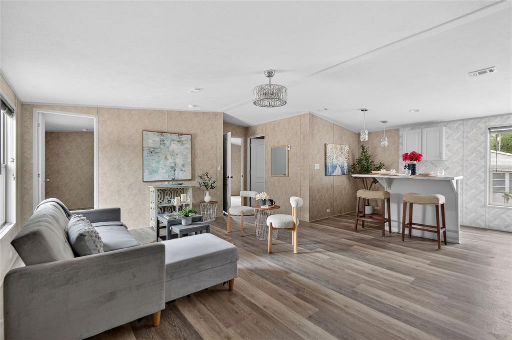 A living room and kitchen area with wood-look flooring, beige walls, and a breakfast bar — 3219 WELSH STREET, SPRING HILL, FL