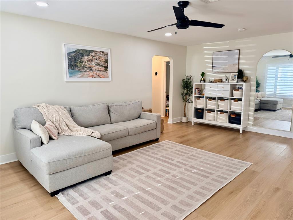 A living room features a gray sectional sofa, a white storage unit, and wood flooring — 6073 TANGLEWOOD DRIVE NE, ST PETERSBURG, FL