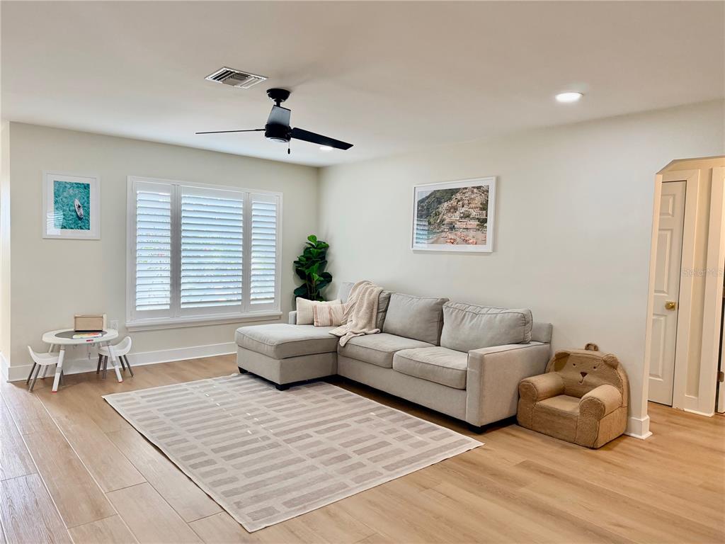 A living room features a grey sectional sofa, a patterned rug, and a children's table — 6073 TANGLEWOOD DRIVE NE, ST PETERSBURG, FL