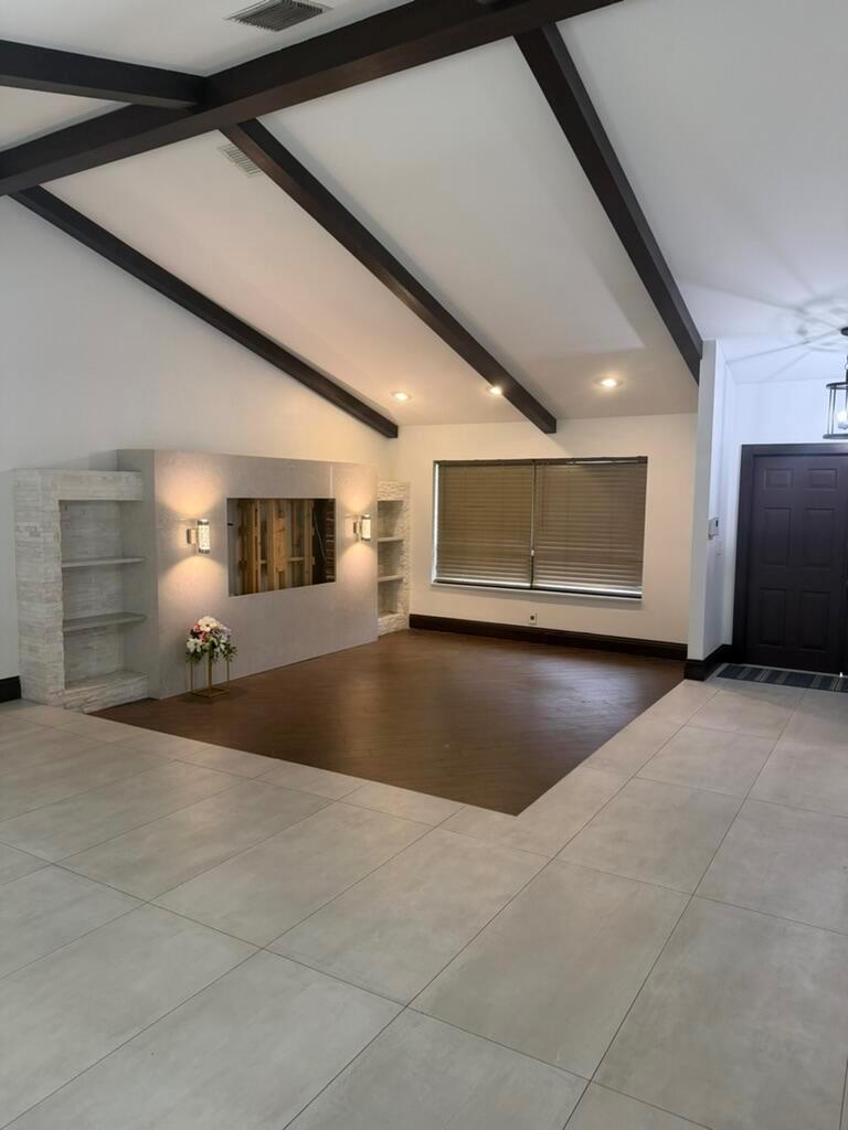 A living room features dark wood ceiling beams, a stone fireplace wall, and mixed flooring — 9553 Majestic Way, Boynton Beach FL 33437, BOYNTON BEACH, FL
