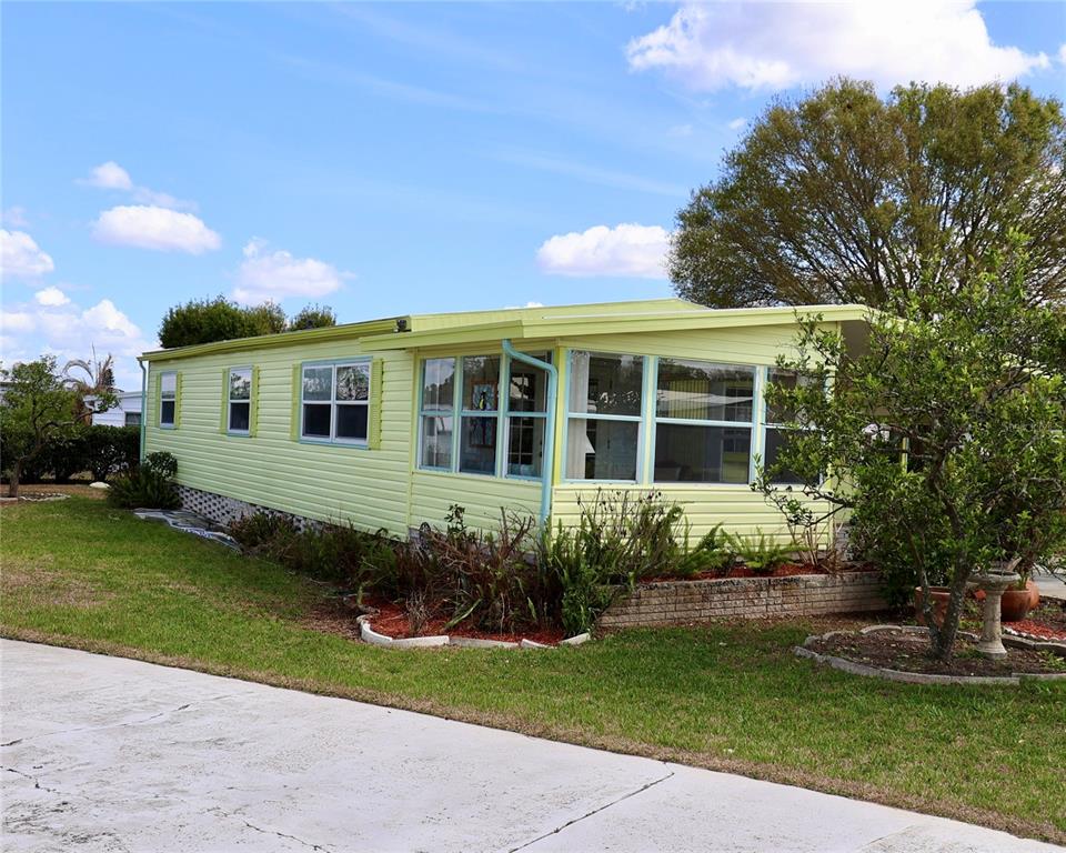 A light green mobile home with a screened-in porch sits on a grassy lot — 1610 REYNOLDS ROAD UNIT 73, LAKELAND, FL