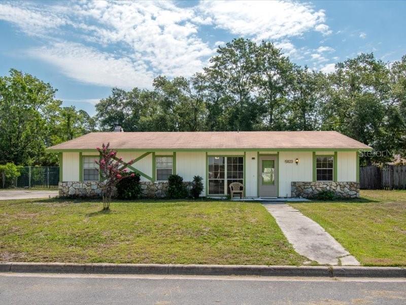 A single-story house with light siding, a stone base, and a green-trimmed roof — 5823 NW 26TH STREET, GAINESVILLE, FL