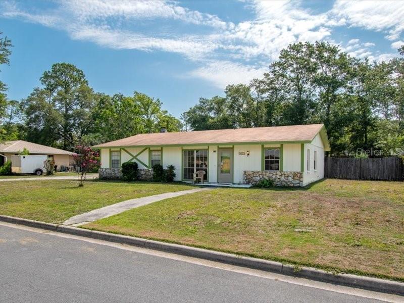A single-story house with a light-colored exterior, stone accents, and a green-trimmed facade — 5823 NW 26TH STREET, GAINESVILLE, FL