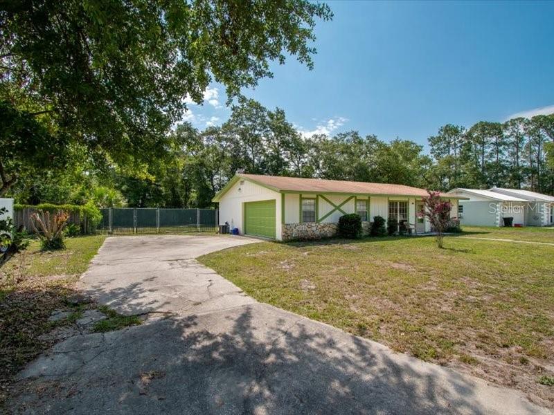 A single-story house with a concrete driveway, stone accents, and a green-trimmed exterior — 5823 NW 26TH STREET, GAINESVILLE, FL